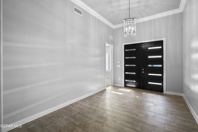 foyer entrance featuring crown molding, a chandelier, wood finished floors, and baseboards