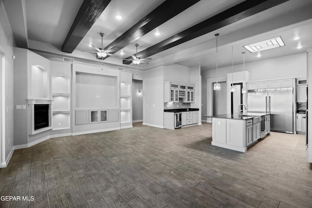 kitchen with dark countertops, ceiling fan, beam ceiling, built in refrigerator, and open floor plan