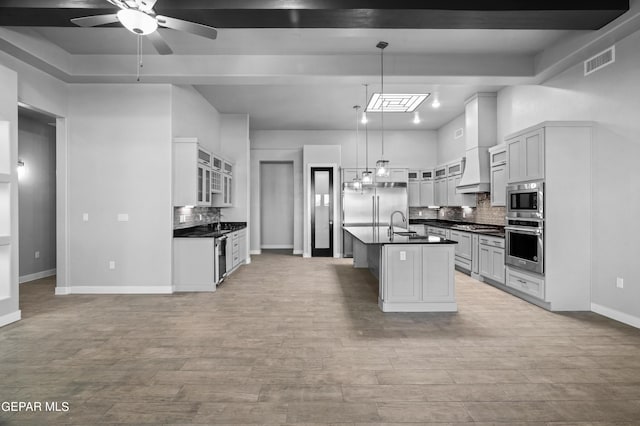 kitchen with built in appliances, dark countertops, ceiling fan, and backsplash
