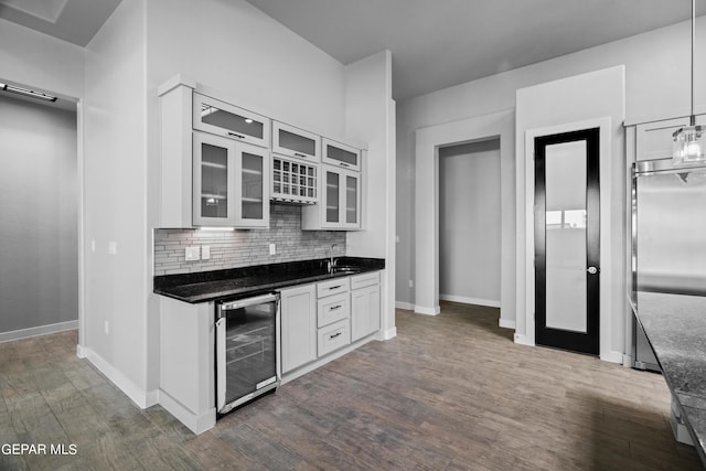 kitchen with beverage cooler, dark wood finished floors, decorative backsplash, and baseboards