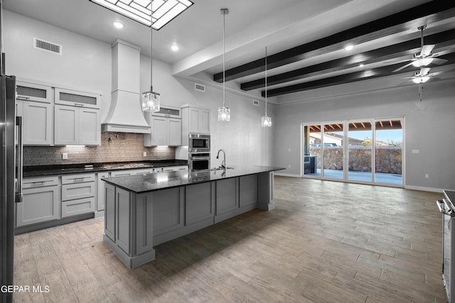 kitchen featuring appliances with stainless steel finishes, beam ceiling, baseboards, tasteful backsplash, and premium range hood