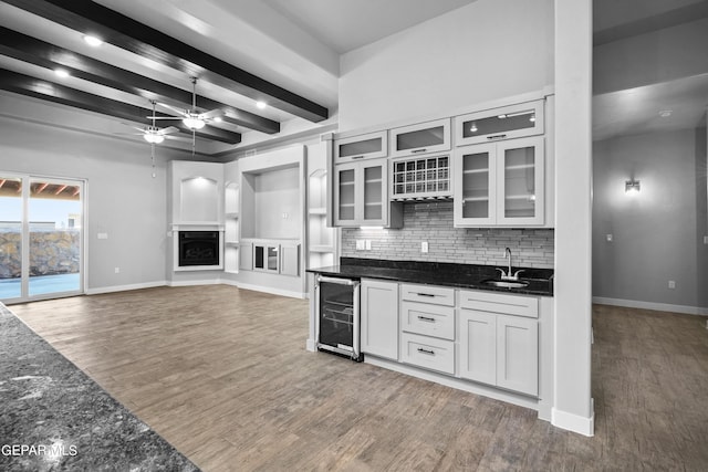 kitchen with wine cooler, a sink, baseboards, a ceiling fan, and wood finished floors