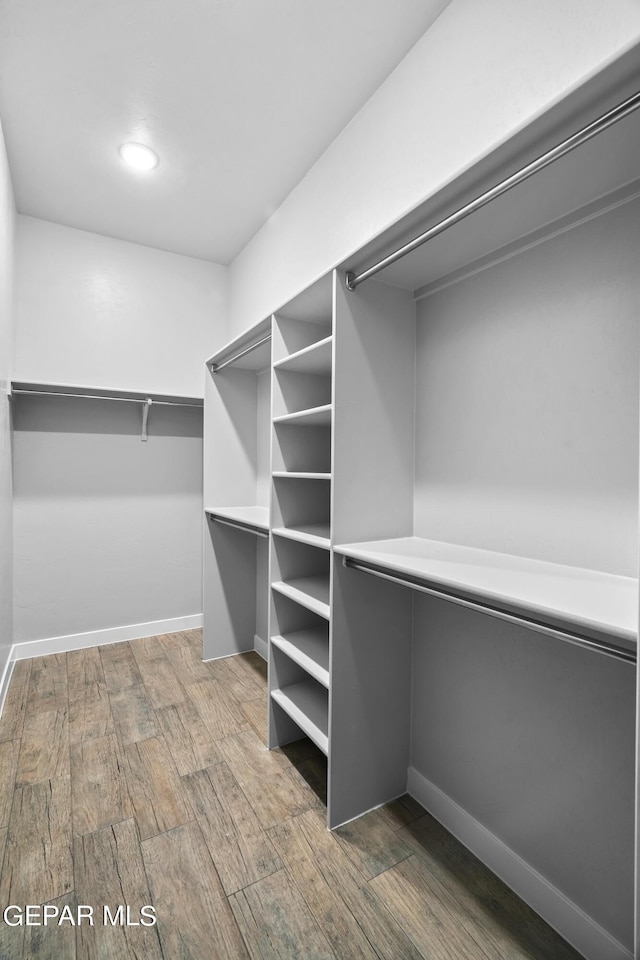 walk in closet with wood finished floors