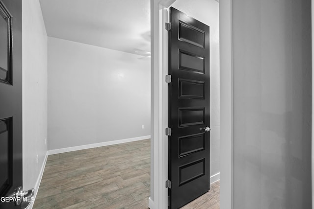 hallway featuring wood finished floors and baseboards