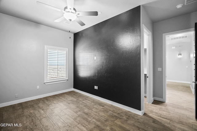 spare room featuring a ceiling fan, wood finished floors, a smoke detector, and baseboards