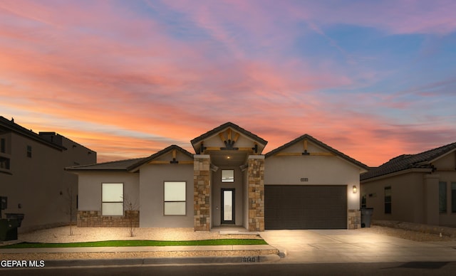 view of front of house featuring stucco siding, stone siding, concrete driveway, and an attached garage