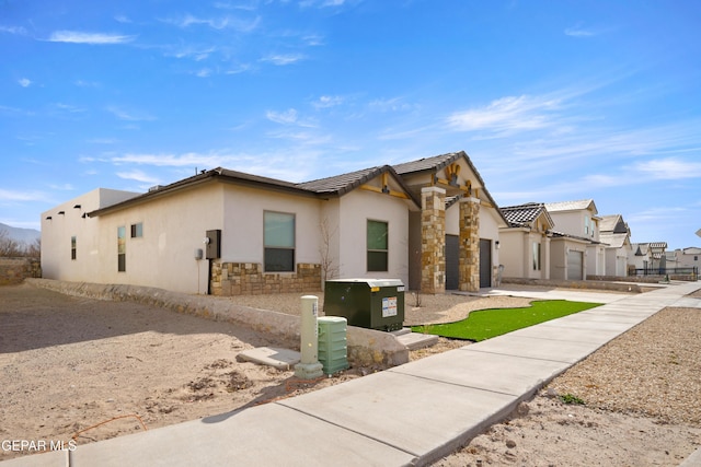 view of front of house featuring stucco siding, stone siding, driveway, and a tile roof