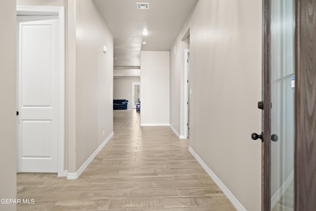 hallway with baseboards, light wood-type flooring, and recessed lighting