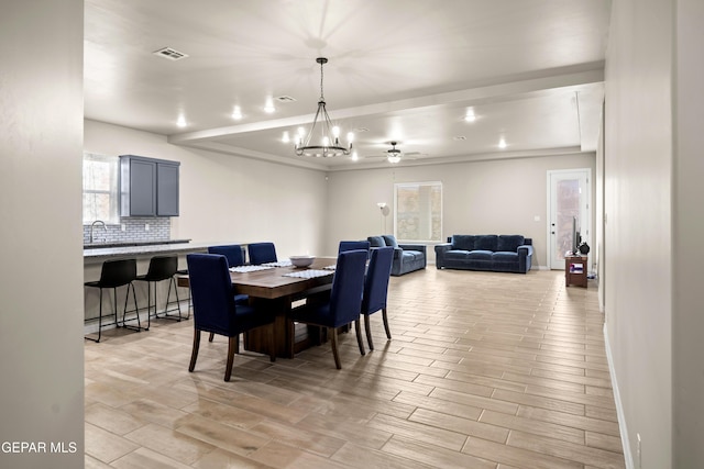 dining room featuring a chandelier, light wood-style floors, baseboards, and ceiling fan
