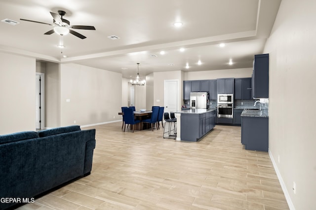 kitchen with appliances with stainless steel finishes, a sink, a chandelier, a kitchen breakfast bar, and a ceiling fan