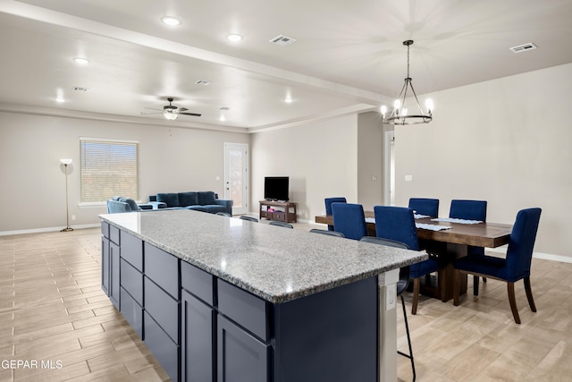 kitchen with baseboards, a center island, ceiling fan, a chandelier, and pendant lighting