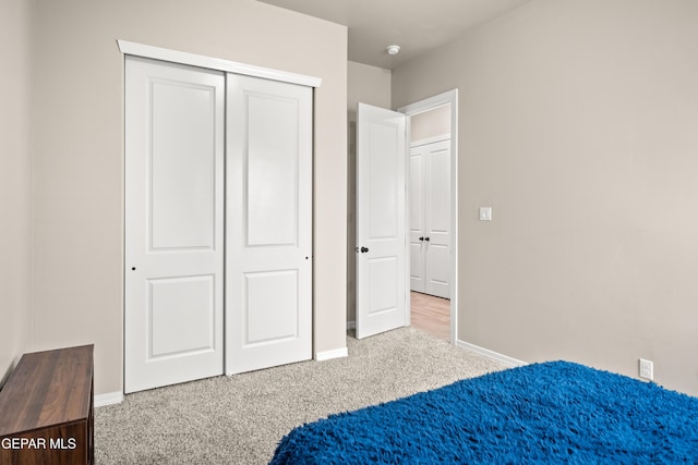 carpeted bedroom with baseboards and a closet