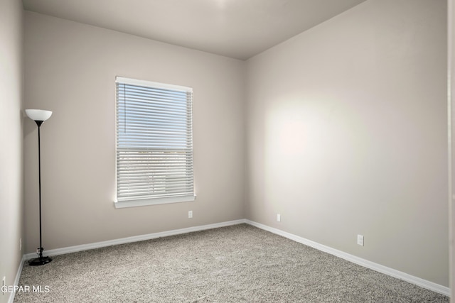 empty room featuring carpet and baseboards