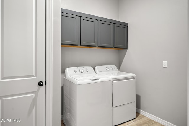clothes washing area with independent washer and dryer, cabinet space, baseboards, and light wood-style flooring