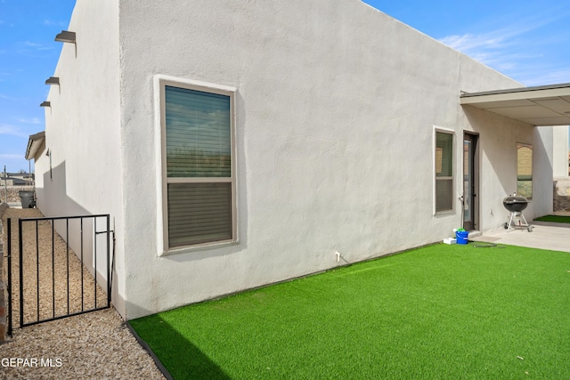 back of property with a patio area, stucco siding, and a gate