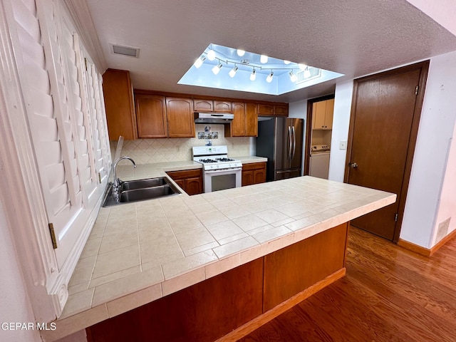 3100 Hector Dr, El Paso, TX 79935 - kitchen featuring freestanding refrigerator, gas range gas stove, washer / clothes dryer, a sink, and wood finished floors