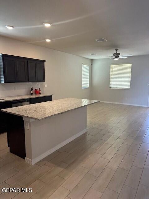 6112 Hidden Row Ave, El Paso, TX 79924 - kitchen with a center island, light stone countertops, baseboards, open floor plan, and a ceiling fan