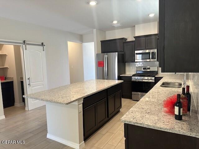6112 Hidden Row Ave, El Paso, TX 79924 - kitchen featuring stainless steel appliances, a sink, a center island, backsplash, and a barn door