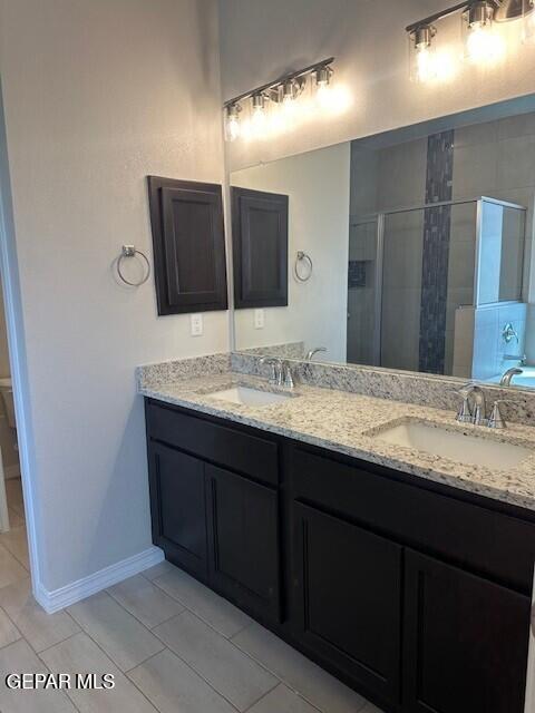 6112 Hidden Row Ave, El Paso, TX 79924 - bathroom featuring a shower stall, double vanity, baseboards, and tile patterned flooring