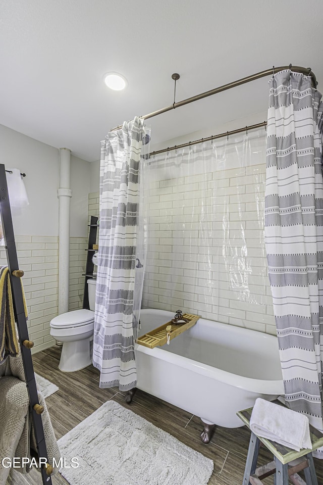 3244 Richmond Ave, El Paso, TX 79930 - bathroom with wood finished floors, tile walls, toilet, shower / bathtub combination with curtain, and a wainscoted wall