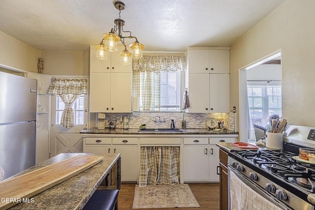 3244 Richmond Ave, El Paso, TX 79930 - kitchen with stainless steel appliances, a sink, dark wood-style floors, dark countertops, and tasteful backsplash