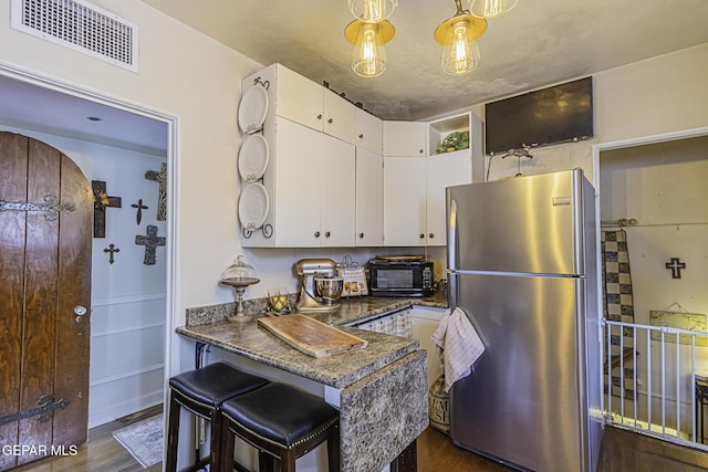 3244 Richmond Ave, El Paso, TX 79930 - kitchen with freestanding refrigerator, black microwave, white cabinets, and dark wood-style floors