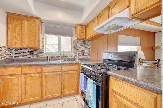 kitchen with gas range oven, a sink, tasteful backsplash, light tile patterned floors, and dark countertops