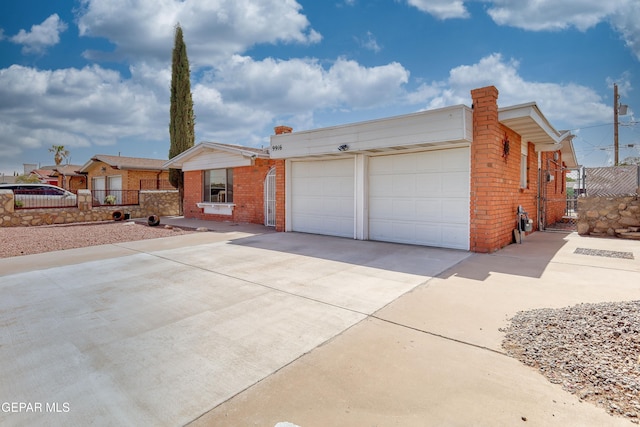 ranch-style house featuring concrete driveway, a garage, brick siding, and fence