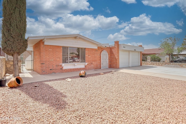 ranch-style home featuring a garage, driveway, brick siding, and fence