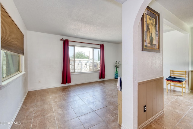 spare room featuring a textured ceiling and light tile patterned flooring