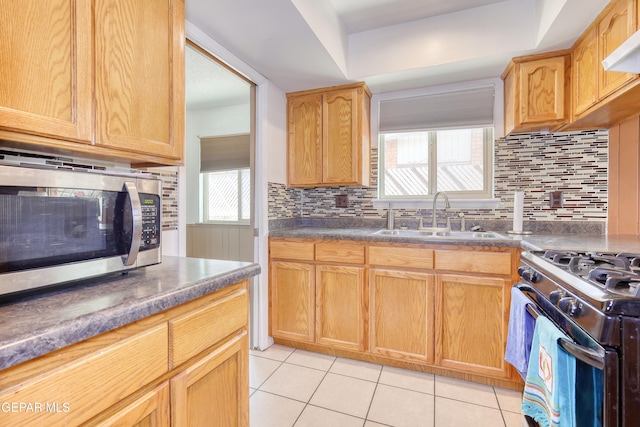 kitchen with stainless steel microwave, a sink, light tile patterned flooring, and backsplash