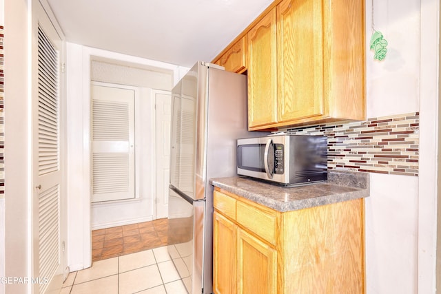 kitchen with appliances with stainless steel finishes, decorative backsplash, light tile patterned flooring, and light brown cabinets