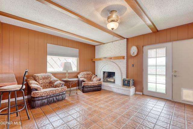 tiled living area featuring a textured ceiling, a fireplace, and beamed ceiling