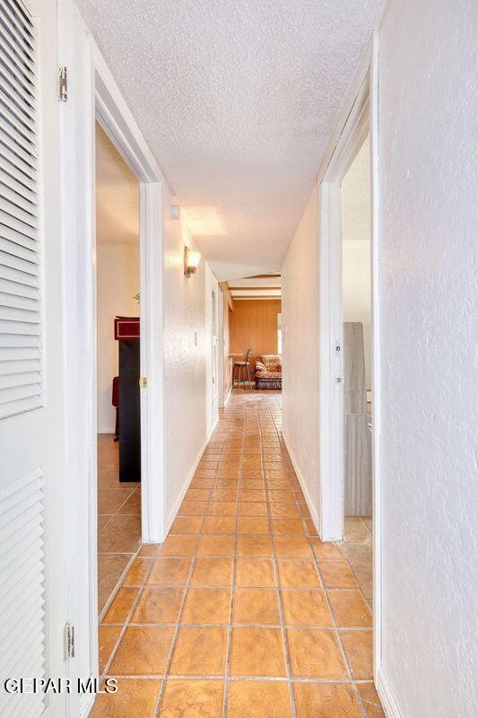 hall with a textured ceiling and light tile patterned floors