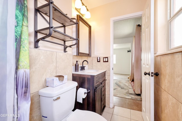 bathroom with tile patterned floors, toilet, vanity, and tile walls
