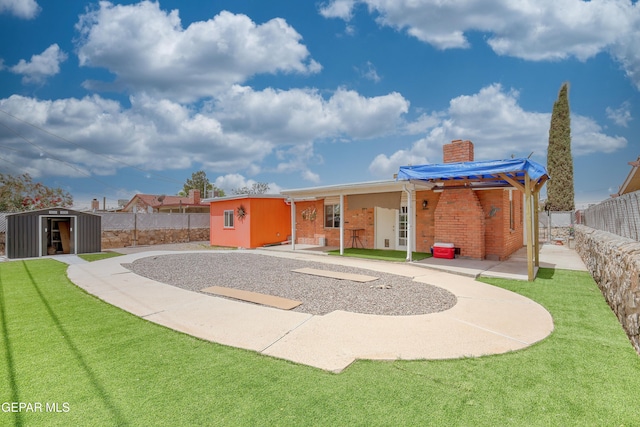 rear view of property with a storage shed, a patio, a chimney, an outbuilding, and brick siding
