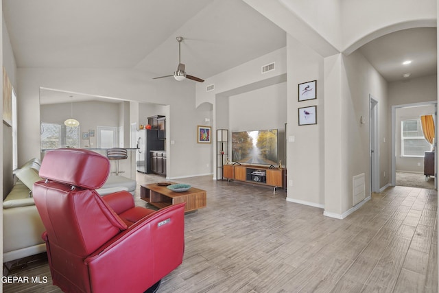7421 Dewberry Dr, El Paso, TX 79911 - living room with arched walkways, a ceiling fan, light wood-style floors, baseboards, and high vaulted ceiling