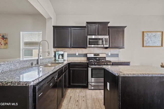 7421 Dewberry Dr, El Paso, TX 79911 - kitchen featuring stainless steel appliances, a sink, tasteful backsplash, a peninsula, and light stone countertops