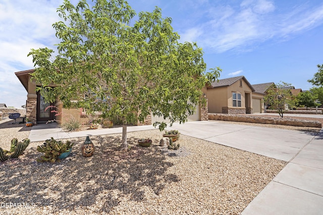 7421 Dewberry Dr, El Paso, TX 79911 - obstructed view of property with stucco siding, concrete driveway, a garage, and stone siding