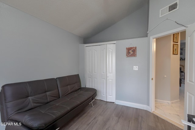 living room featuring lofted ceiling, wood finished floors, and baseboards