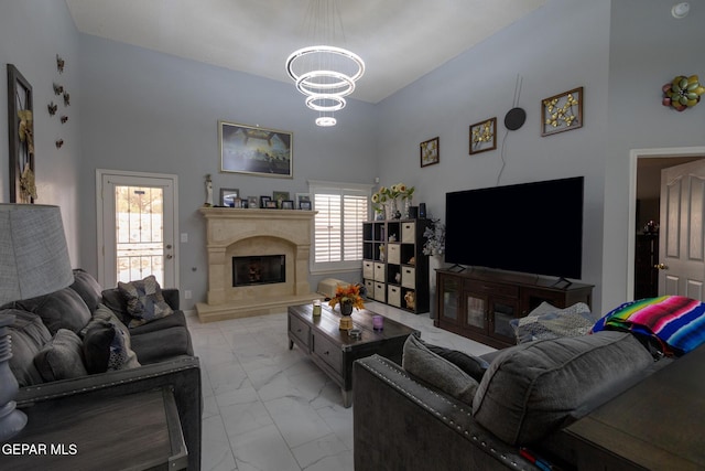 living room with light marble finish flooring, a chandelier, and a high end fireplace