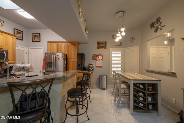kitchen with stainless steel appliances, light marble finish floors, a kitchen bar, baseboards, and dark stone counters