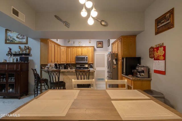 kitchen featuring stainless steel appliances, a peninsula, and light marble finish floors