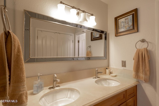 bathroom with double vanity and a textured wall