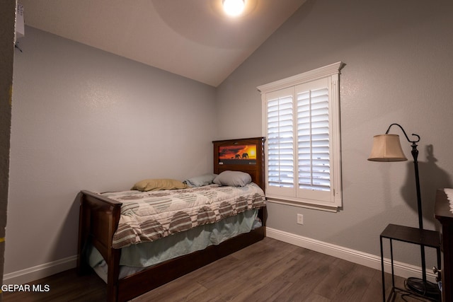 bedroom with vaulted ceiling, wood finished floors, and baseboards