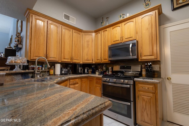 kitchen featuring stainless steel appliances, a sink, decorative backsplash, and dark countertops