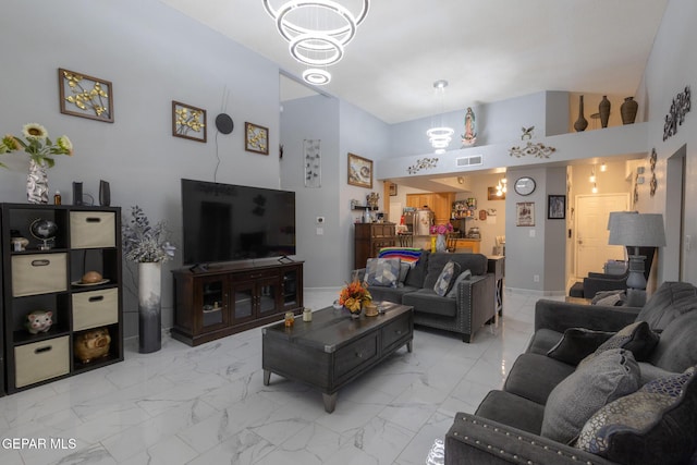 living room featuring a chandelier, light marble finish floors, high vaulted ceiling, and baseboards