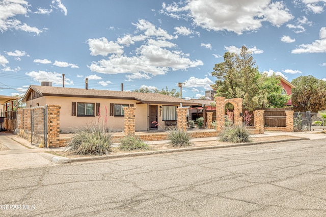 view of front of home featuring stucco siding, fence, and a gate
