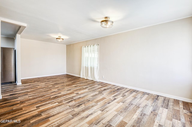 unfurnished room with wood finished floors, baseboards, and crown molding