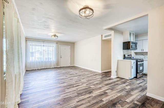 unfurnished living room featuring wood finished floors and baseboards